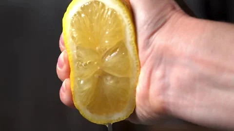 Human squeezes lemon as fresh lemon juice pours in his hand. squeezing a le.. Stock Footage 265838529