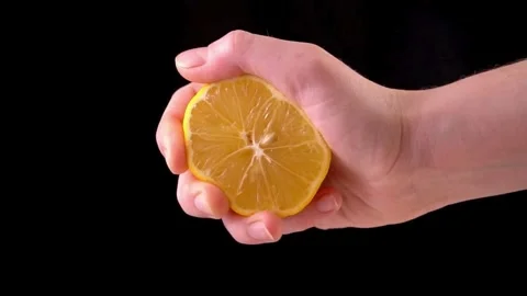 Human squeezes lemon as fresh lemon juice pours in his hand. squeezing a le.. Stock Footage 265838875
