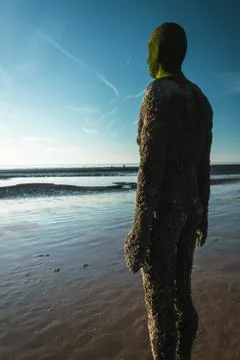 Human Statue Placed on Beach Looking Out Over the Ocean Stock Photos