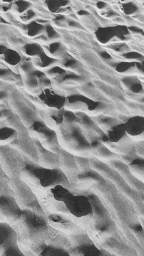 Human steps on dark volcanic beach surface Stock Photos