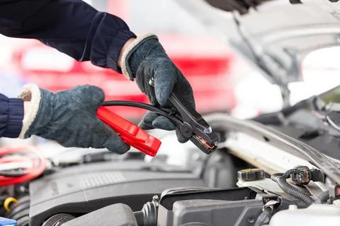 Human trying to start engine with jumper cables in close up Stock Photos