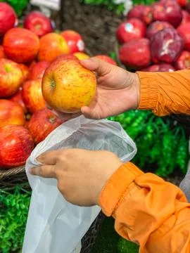 Human using bioplastic bag when buying apples at grocery store Stock Photos