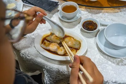 Human using chopsticks while eating Chinese steamed shrimp rolls Foto stock