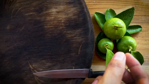 Human using kitchen knife slice cut green lemon on wood cutting board Stock Footage 129009609