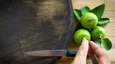 Human using kitchen knife slice cut green lemon on wood cutting board Video stock 129009622