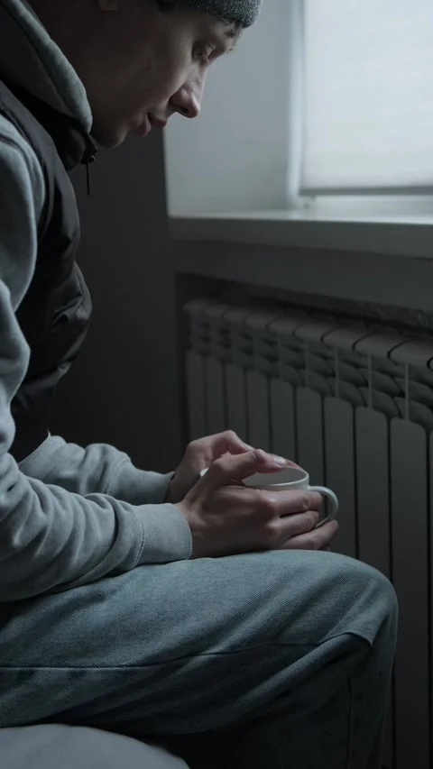 Humanitarian crisis concept, man warming hands near radiator in cold apartment Stock Footage 329626543