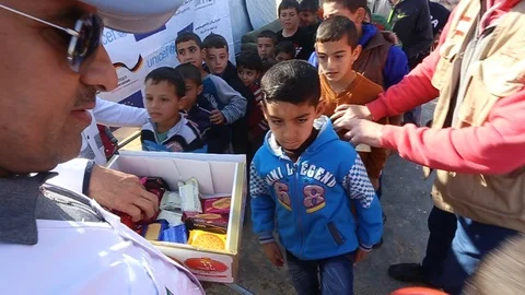 Humanitarian worker giving candy to refugee kids Stock-Footage 96032932