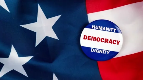 Humanity democracy dignity text on campaign button laying on the american fla Stock Footage 170943810