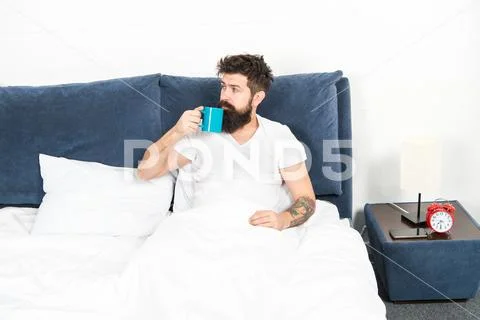 Humanity runs on coffee. Man brutal handsome hipster relaxing bedroom drink Stock Photos