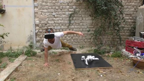 A humanoid android robot and a young man exercise push ups Stock Photos