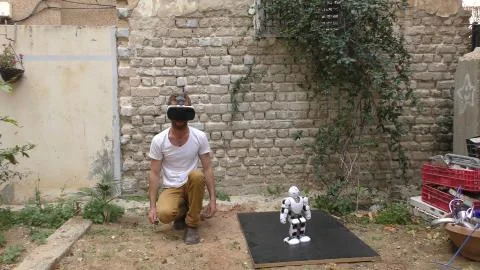 A humanoid android robot and a young man exercise push ups Stock Photos