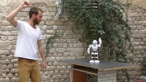 A humanoid android robot teaches a young man to dance Stock Photos