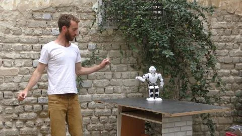 A humanoid android robot teaches a young man to dance Stock Photos