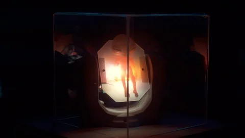 Humanoid cosmos creature rotates around glass cube the laser illuminates it. Red Stock Footage 98865536