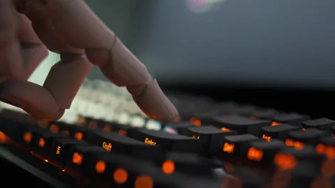A humanoid cyborgs robotic hand moves swiftly over a keyboard pressing keys Stock Footage 331475343