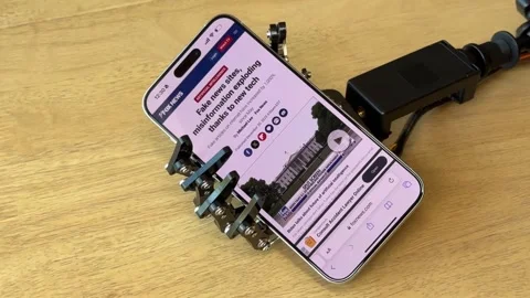 Humanoid Robot Hand Holding Smartphone Displaying News Article Stock Footage 280009732