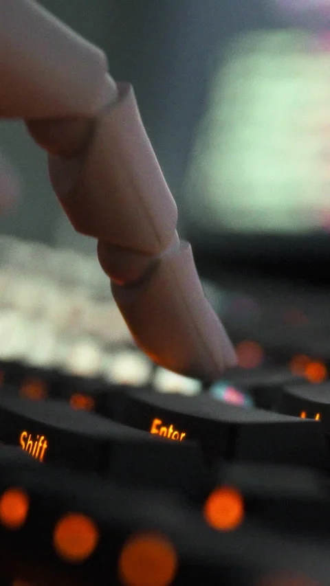 A humanoid robot with precision-built mechanical fingers types on a computer Stock Footage 347279360