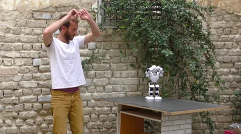 A humanoid robot teaches a young man to dance.  Видео 60985252