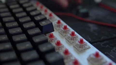 A human's hand assembles the keys of a mechanical keyboard with red switches Stock Footage 194561392