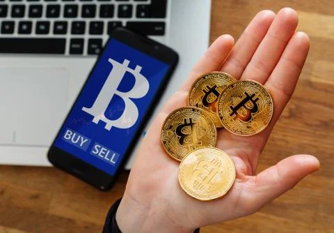 Human's hand holding gold coin of Bitcoin and Virtual currency symbol on mobi Stock Photos
