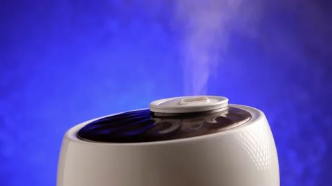 Humidifier generates vapor on blue background. Steam from working air purifier. Stock Footage 169019706