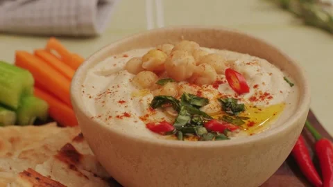 Hummus among fresh vegetables on table close-up. Hummus garnished with chickpeas Stock Footage 265163549
