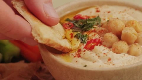 Hummus among fresh vegetables on table close-up. Hummus garnished with chickpeas Stock Footage 265163944