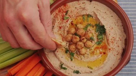 Hummus among fresh vegetables on table top view. Hummus garnished with chickpeas Stock Footage 265164255