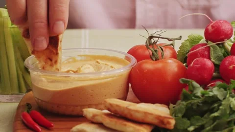 Hummus among fresh vegetables on table close-up. Dipping vegetable slice in Stock Footage 266959879
