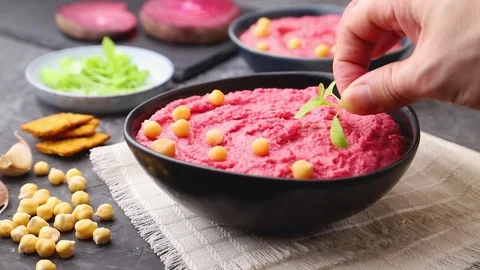 Hummus with beet  in blue ceramic bowl decorated with microgreen basil sprouts. Stock Footage 127058822