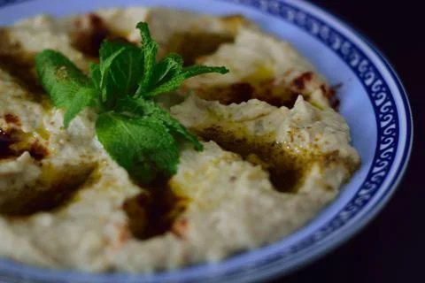 Hummus bowl with blue edge, decorated with herbs and olive oil Stock Photos