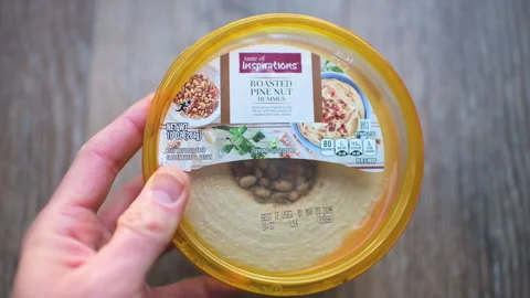Hummus tahini chickpeas, roasted pine nuts topping hand holding closeup Stock Footage 336781071
