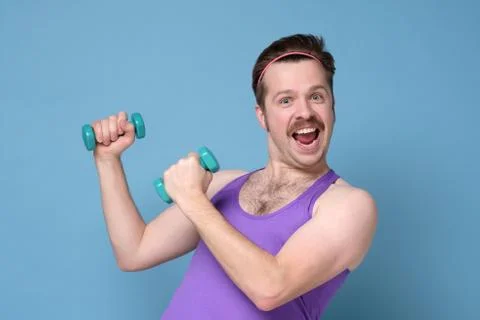 Humorous athletic man using small dumbbells for bodybuilding Stock-Fotos
