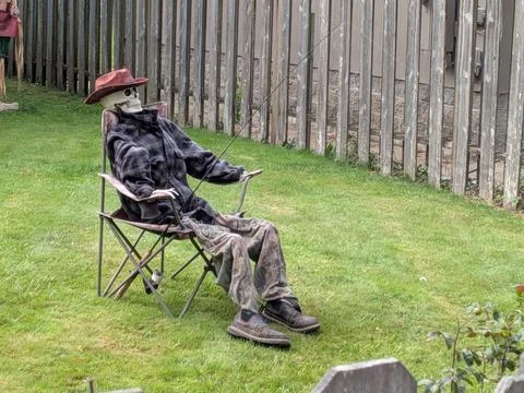 Humorous display of a dressed skeleton seated on a chair with fishing gear Stock-Fotos