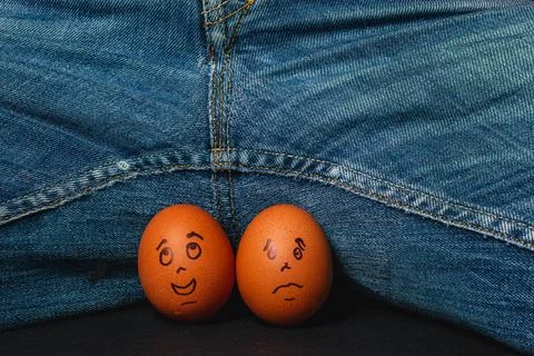 Humorous eggs with faces placed under denim jeans Stock Photos