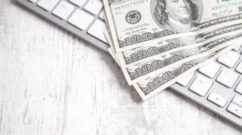 Hundred dollar banknotes with a computer keyboard. Stock Photos