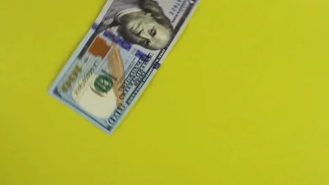 Hundred dollar bills fall on the rotating table and continue to spin. Backgro Stock Footage 84739500