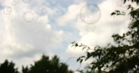 Hundreds of bubbles floating in the air with blue skies and green trees Stock Footage 207338858