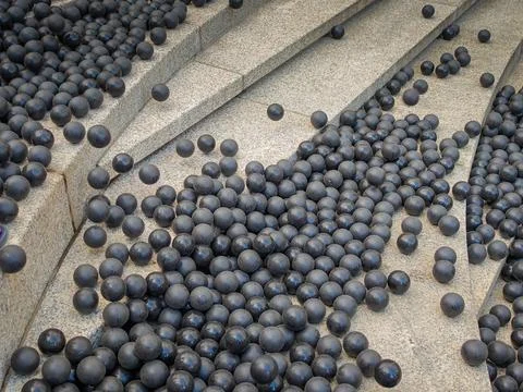 Hundreds or thousands of black rubber balls laying on the stone stairs in street Stock Photos