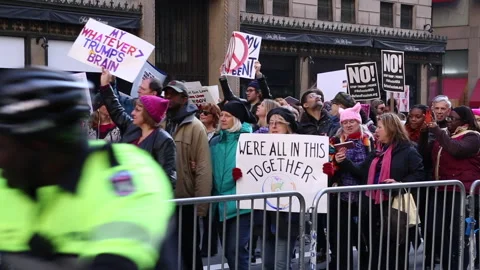 Hundreds of protestors march up 5th Ave carring signs against Trump Stock Footage 260352689