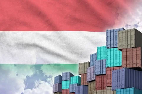 Hungary flag and big stack of shipping cargo containers in docks with sky Stock Photos