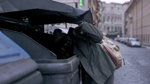 Hunger, misery, poverty-bum rummages in the dumpster in the street Stock Footage