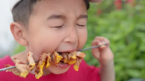 Hungry boy biting chicken BBQ from skewer. Stock Footage 194370275
