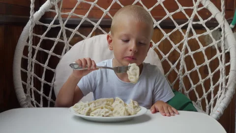 Hungry Boy Eagerly Eating Delicious Dumplings For Lunch In Hanging Chair Stock Footage 321677667