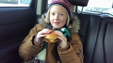 Hungry Boy Eats Cheeseburger in Winter Stock Footage 144736634