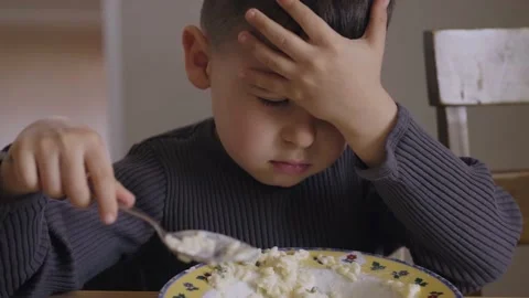 Hungry boy enjoying corn flakes on breakfast in the morning sitting at wooden Stock Footage 202022645