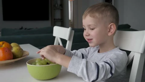 Hungry Boy Picks Berries With Hands Green Grapes At Kitchen Table Sweet Fruits Stock Footage 234177555