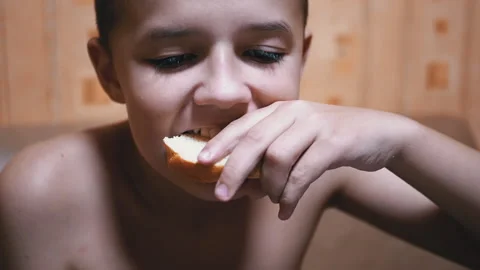 Hungry Child Bites Off a Piece Bread and Eat It. Fast Food at Home in Kitchen Stock Footage 142037969