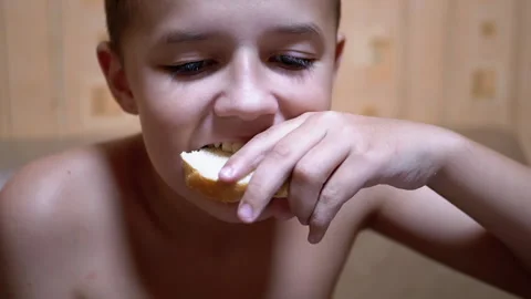 Hungry Child Bites Off a Piece Bread and Eat It. Fast Food at Home in Kitchen Stock Footage 142229560