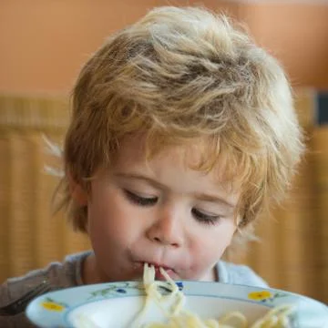 Hungry child eats lunch with big appetite. Nutrition for healthy children. Ba Stock Photos